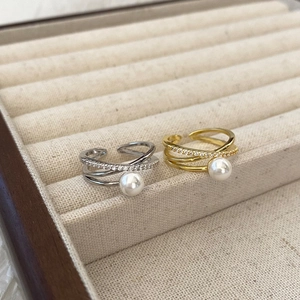 Détail de bagues croisées avec perles blanches et zircons en finition or et argent
