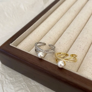 Bagues croisées élégantes avec perles et zircons en or et argent sur bois