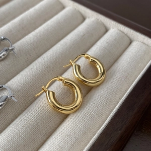 Détail de boucles d'oreilles Huggie polies en forme de U, finitions dorée et argentée