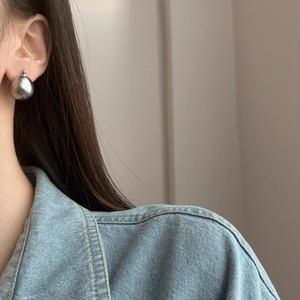 Orecchini a perno geometrici a sfera opaca spazzolata in argento indossati da modella