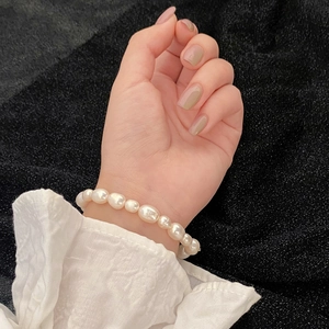 Bracelet en perles d'eau douce baroques et accents dorés au poignet d'une femme