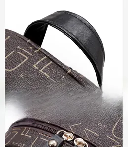 Detail view of the brown monogram backpack featuring a reinforced black handle and gold zipper
