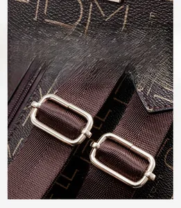Close-up of brown letter printed fabric and metal adjustment buckle on backpack strap