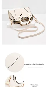 Detail of elegant cat-ear shaped gold metal handle and fine stitching on white tote bag