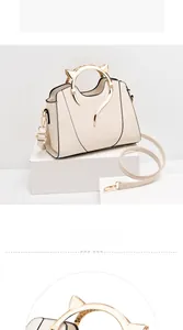 Detailed close-up of cream white handbag featuring golden cat-ear shaped metal handles