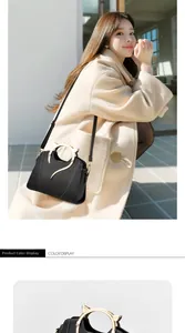 Detail of black handbag with cat-ear golden metal handles and detachable shoulder strap