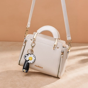 Elegant cream leather handbag with gold logo, daisy pendant, and adjustable shoulder strap