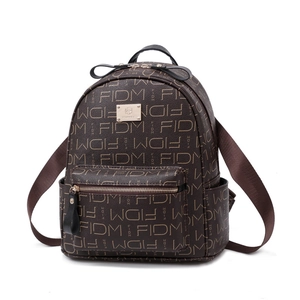 Brown vintage backpack with FIDM monogram print and gold logo plaque on white background