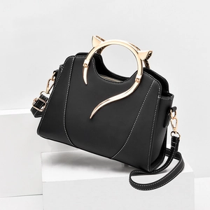 Chic black handbag with cat ear metal handles and white stitching on display
