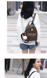 Brown backpack with letter pattern and white fur ball pendant shown in city outdoor use