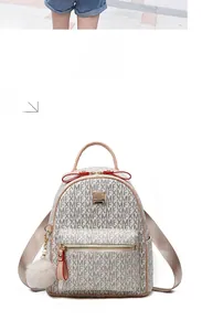 Close-up of beige monogram backpack with pink handle, red bow, and plush charm detail