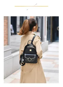 Detail of small black faux leather backpack with gold geometric buckle and plaid charm