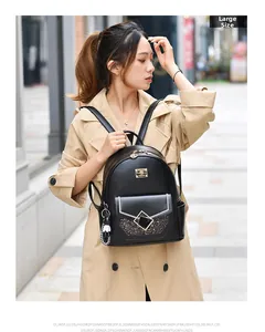 Detail of black PU leather backpack featuring glitter pocket and white cartoon charm accessory