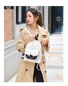 Small size white PU leather backpack with diamond buckle and cartoon pendant shown on model