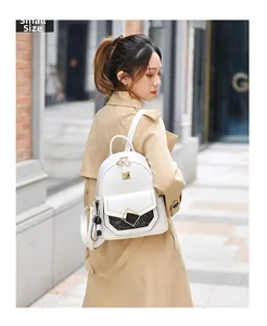 Small white leather backpack with gold heart zipper and sequined pocket details on model
