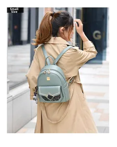 Sage green small backpack with grain texture and black bear pendant shown on model