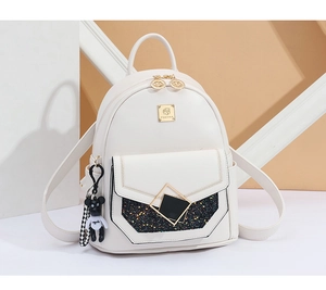 Detail of cream leather backpack featuring golden buckle and cute bear charm accessory