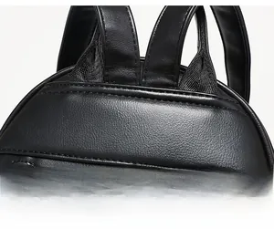 Detail of reinforced shoulder strap stitching and headphone jack on black leather backpack