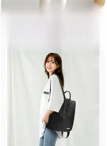 Détail d'un sac à dos noir en nylon imperméable avec logo en métal porté par un mannequin