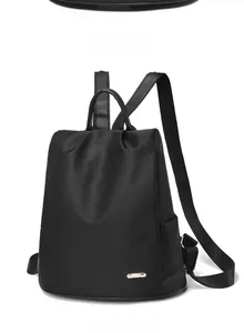 Détail macro du sac à dos en nylon noir avec plaque logo en métal doré poli et texture