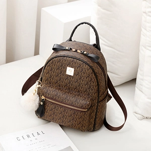 Brown vintage faux leather backpack with monogram pattern and white plush ball charm