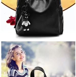 Close-up of black lychee grain leather backpack with a trendy bear keychain detail