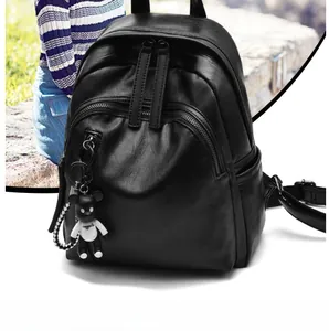 Detail of black lychee grain leather backpack with multiple zippers and a doll charm