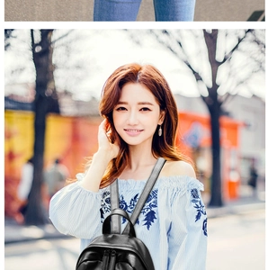 Detail of a black soft leather backpack styled with a blue floral embroidered striped top