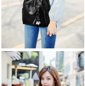 Detailed view of black leather backpack featuring dual zippers and cute bear charm pendant