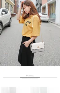 Detail of crossbody bag featuring pearl cat buckle and elegant gold chain strap