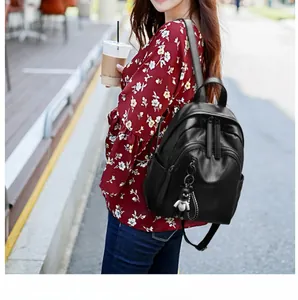 Outdoor street shot of a black soft leather backpack with a trendy doll charm detail