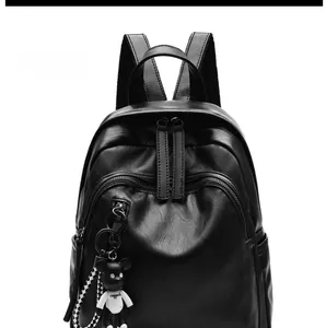 Front view of black soft leather backpack featuring a cute bear charm and checkered strap
