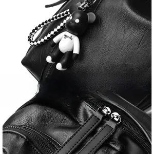 Detail of black pebbled leather backpack with double zippers and cute bear charm pendant
