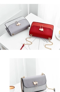 Detail of gray and red crossbody bags featuring cat pearl pendants and metal chains