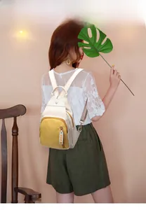 Mini yellow Oxford cloth backpack with FIDM tag and detachable straps shown on model
