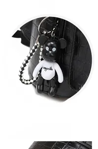 Detail of crocodile pattern leather backpack with double zippers and bear pendant