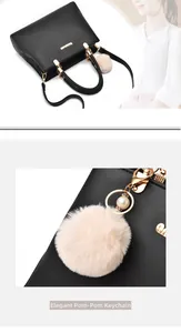 Detail of elegant beige pompon with pearls on a black leather handbag with gold hardware