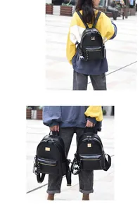 Detail view of black crocodile pattern faux leather backpack with gold zippers and charm