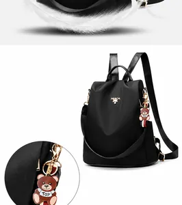 Detalle de mochila de nailon negro impermeable con logotipo metálico y colgante de oso