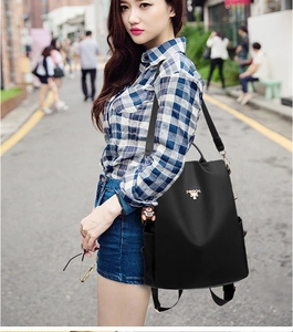 Detalle de mochila de tela Oxford negra impermeable con colgante de oso y antirrobo