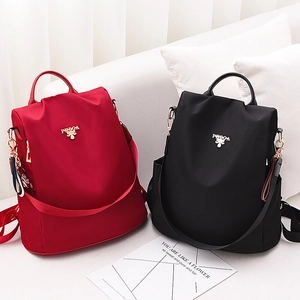 Mochila de nailon impermeable para mujer en rojo y negro con logo metálico y colgante de oso