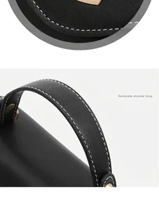 Makroaufnahme einer schwarzen Lederhandtasche mit Kontrastnähten und Goldmetall-Beschlägen