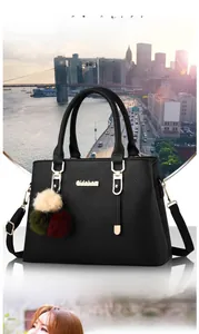 Detail of black pebbled leather handbag with gold hardware and colorful pompom charm
