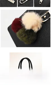 Close-up of black lychee texture handbag with golden hardware and tricolor pompom charm