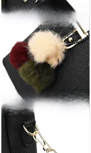 Detail of black lychee grain leather handbag with removable colorful pompom and gold hardware