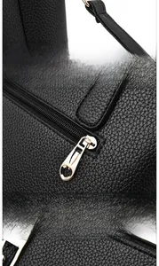 Detail of golden polished metal buckle and hardware on black lychee grain leather handbag