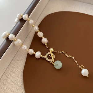 Close-up of baroque pearl bracelet with gold OT clasp and green jade pendant detail