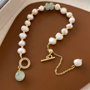 Detailed close-up of Baroque freshwater pearls and green jade beads with gold OT clasp
