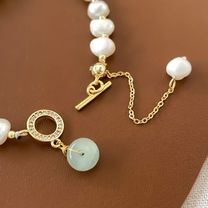 Detail of baroque pearl bracelet with gold OT buckle and green jade donut charm
