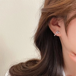 Nahaufnahme glitzernder Knoten-Ohrstecker mit Zirkonia am Ohr des Models